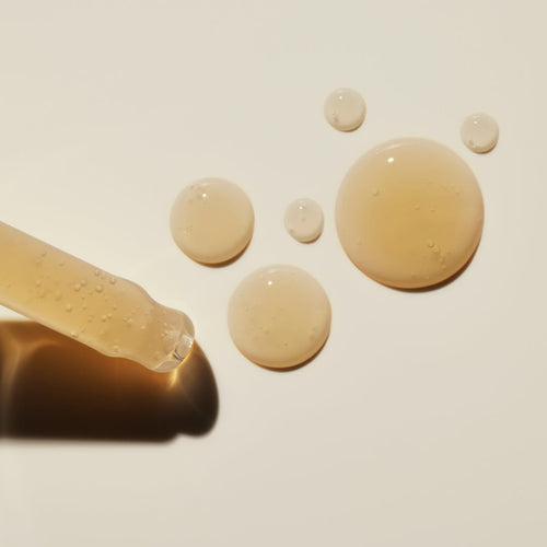 Close-up of Eternal Renewal Face Serum dropper with serum on a light beige background.