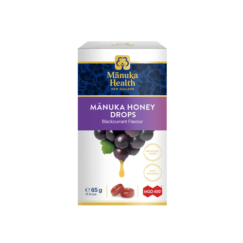 A box of Mânuka Health Mânuka Honey Drops in blackcurrant flavour, featuring a white and purple design with an illustration of blackcurrant grapes and a honey drop.